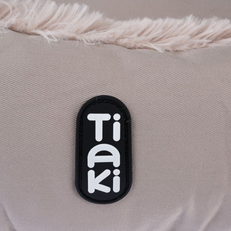 Tiaki logo on beige fabric with faux fur trim.