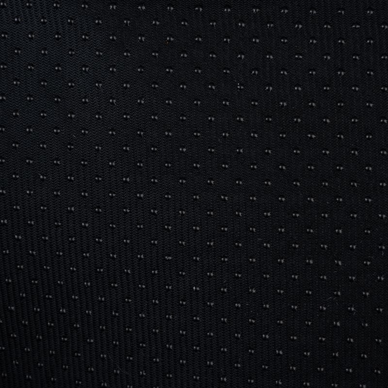 Close-up of black fabric with small, regular dots. Material texture visible.