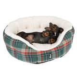 Dog sleeping in a soft, checked dog bed with white inner lining. Trixie brand logo visible on the outside of the bed.