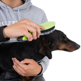 Person brushing a dog with a green brush, showing use of the grooming product.
