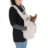 Person carrying a grey fleece carrier bag with a small dog inside. Bag has adjustable straps and drawstring.