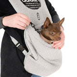 Carrier bag made of grey fleece with safety clip, suitable for small dogs. Dog sits securely in the bag while person holds the clip attachment.