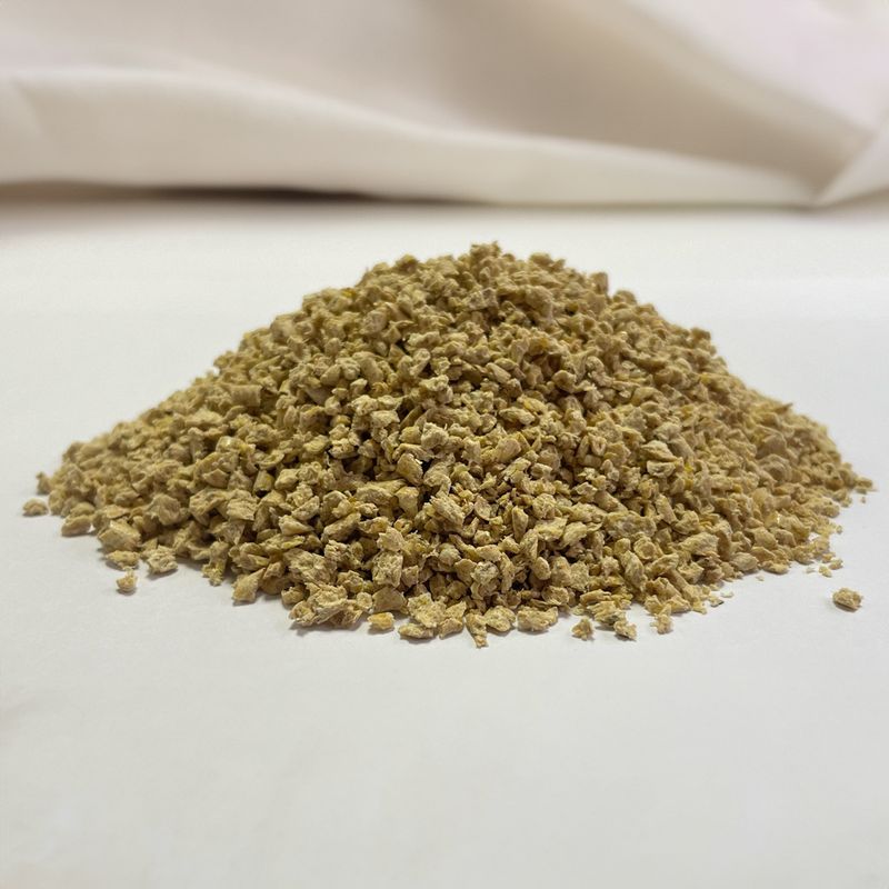 Close-up of loose, light brown granules on a white surface.