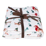 White blanket with dog motifs and fir trees, tied with brown gift ribbon.