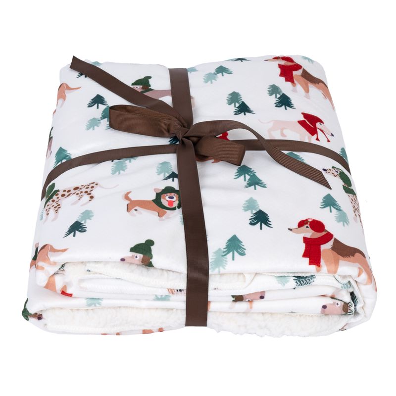 White blanket with dog motifs and fir trees, tied with brown gift ribbon.