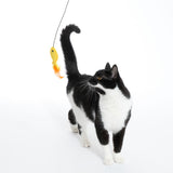 Black and white cat playing with a yellow toy fish on a string, suitable for interactive play.