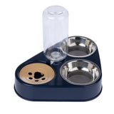 Triangular food and water dispenser with two stainless steel bowls and a transparent water container. Beige paw motif on the base.