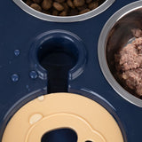Close-up of a feeding toy with two stainless steel bowls filled with dry food and wet food, and a yellow play element on a blue surface.