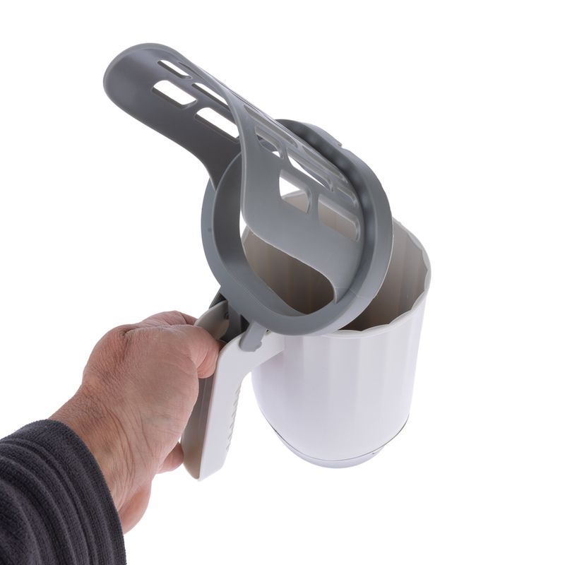 Hand holding a white measuring cup with grey handle and sieve lid, suitable for dosing pet food or other materials.