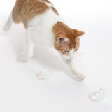Red and white cat playing with transparent, glittery play balls on white background.