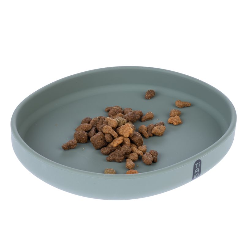 Round, green feeding bowl with dry food pieces. Bowl made of smooth material, brand logo 'Tia' visible on the rim.