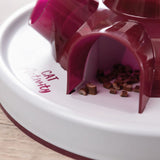 Toy with the inscription 'Cat Activity', red plastic design, compartments with small treats visible.