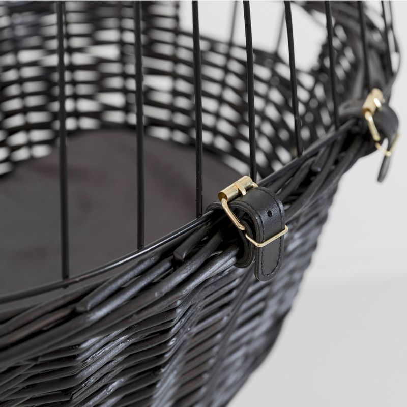 Close-up of a black wicker basket with metal mesh and leather strap with gold-coloured buckles.