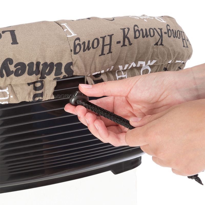 Hand tightens a black drawstring on a brown cover with a script pattern, placed over a black plastic container.