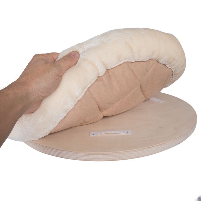 Hand showing removable beige-white cushion with hook-and-loop fastener on a round wooden board.