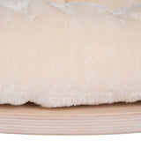 Close-up of soft, cream-coloured plush material on a wooden base.