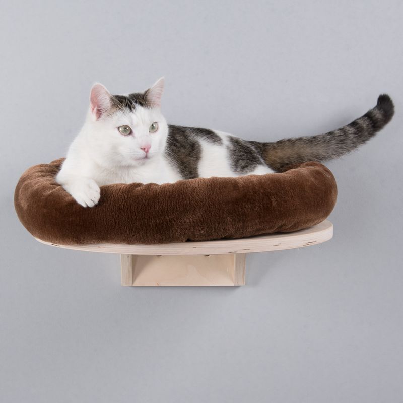 Brown, round cat bed made of plush, mounted on a wooden wall bracket.