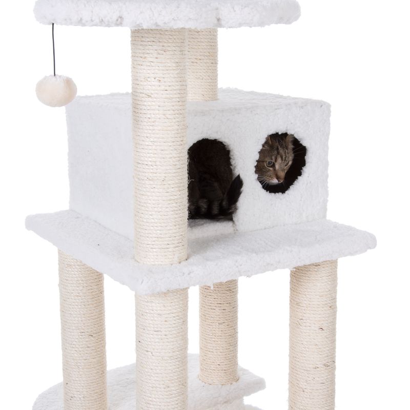 Cat tree with white plush cover, sisal posts and cave. Cat looks out from an opening in the cave.