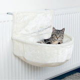 Cat bed made of white plush, attached to a radiator. Grey cat lying relaxed in the bed.