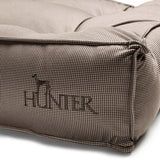 Close-up of a brown dog cushion with houndstooth pattern and embroidered 'Hunter' logo with dog silhouette.