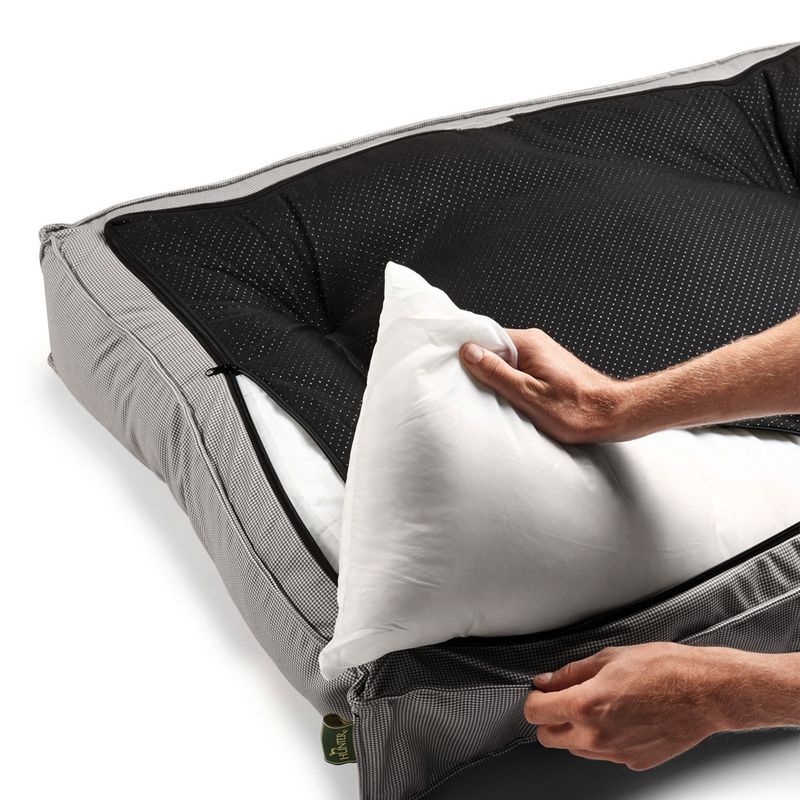 Hand showing removable cushion from a dotted black interior of a grey pet bed with zip.