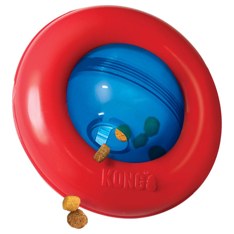 Red and blue treat dispenser toy with dry food pieces falling out, showing how treats are released from the opening during play.