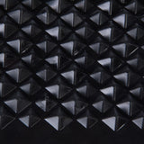 Close-up of a black surface with pyramid-shaped elevations, possibly material structure of a product.