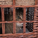 Brown basket made of woven wood with a cat looking through the bars.