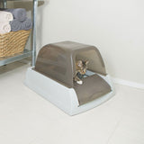 Cat using an enclosed litter box with a transparent front flap, demonstrating product function and entry design.