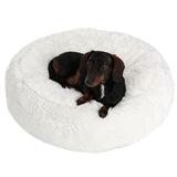 Dog lying on a white, fluffy pet bed. Round design with soft surface.