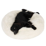 Black dog lying on a large, round, fluffy white pet bed, demonstrating the size and comfort of the product.