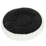 Round, white pet bed with black fabric lying surface. Outer area with soft fur look.