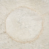 Close-up of soft, cream-coloured faux fur material with a circular pattern, showing texture and surface detail.