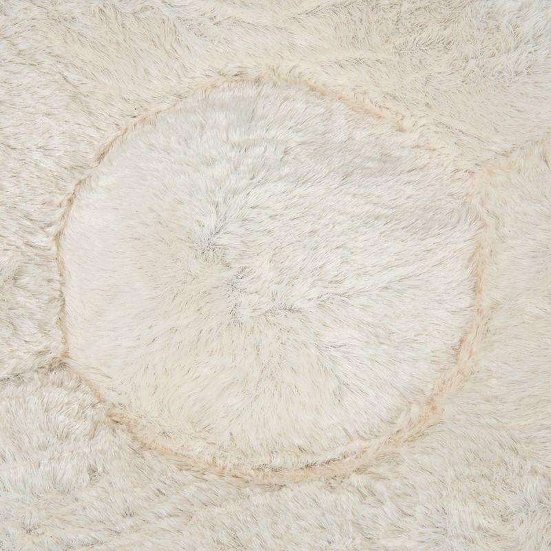 Close-up of soft, cream-coloured faux fur material with a circular pattern, showing texture and surface detail.