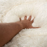 Hand pressing into soft, fluffy white material to demonstrate thickness and plush texture of the product surface.