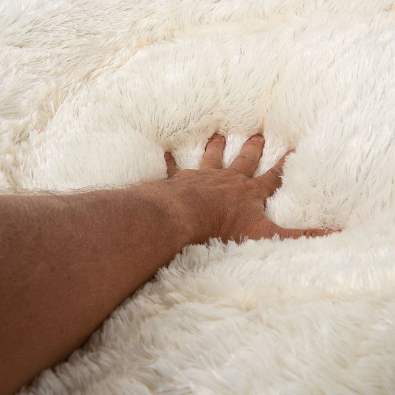 Hand pressing into soft, fluffy white material to demonstrate thickness and plush texture of the product surface.