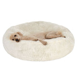 Animal lying on a large, round, fluffy cream-coloured bed, demonstrating the use and size of the product.