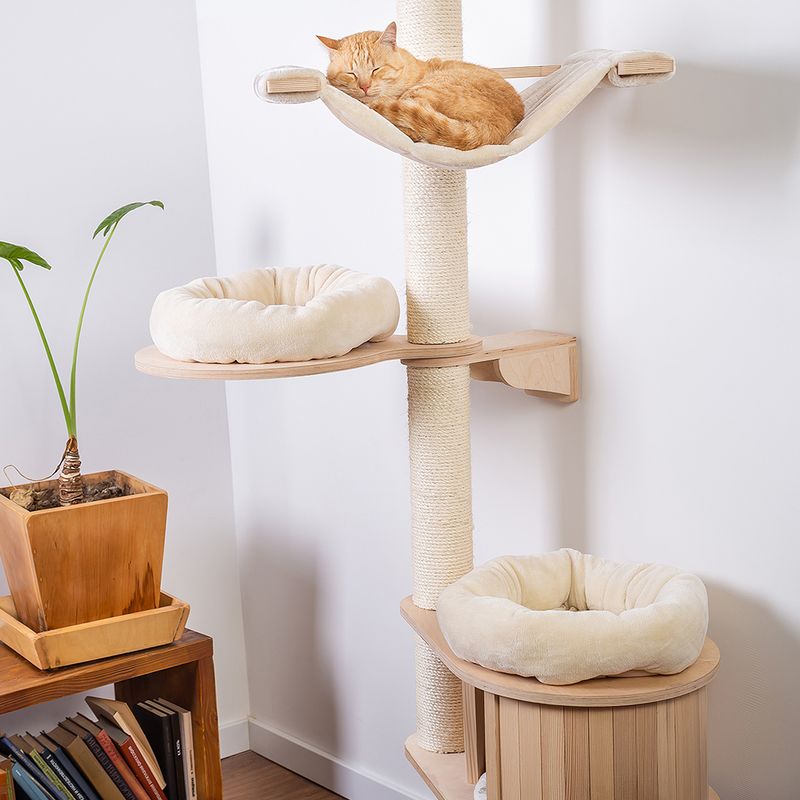 Cat tree made of wood with three levels, sisal scratching post and beige resting areas. A cat is sleeping on the top hammock.