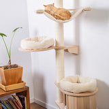 Cat tree made of wood with three levels, sisal scratching post and beige resting areas. A cat is sleeping on the top hammock.