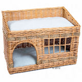 Braided basket with two levels, lower level with entrance and upper level with white cushion. Made of rattan.