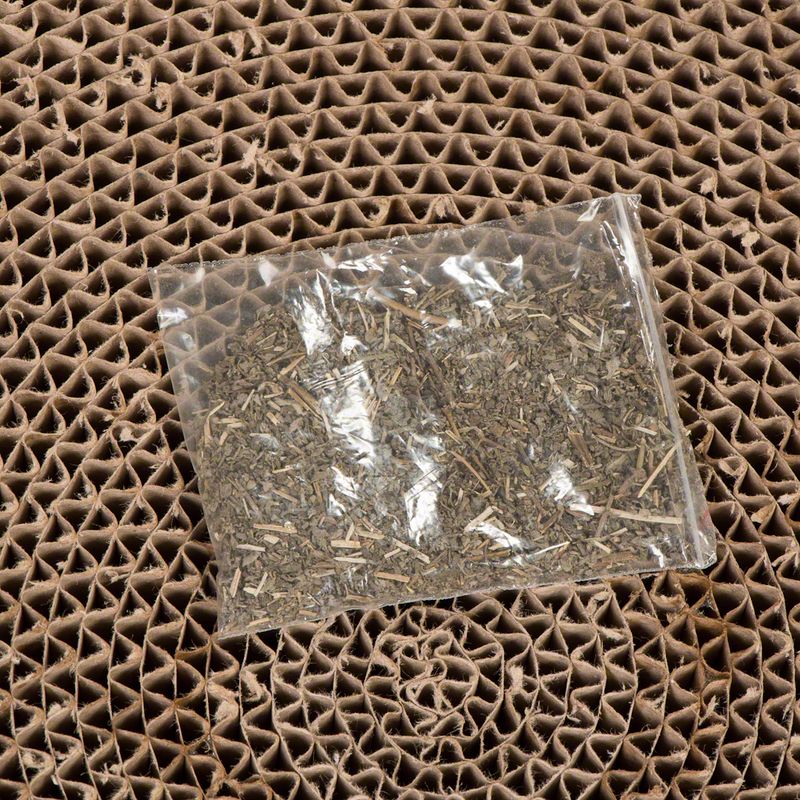 Transparent pouch with dried herbs on a brown, honeycomb-shaped cardboard base.