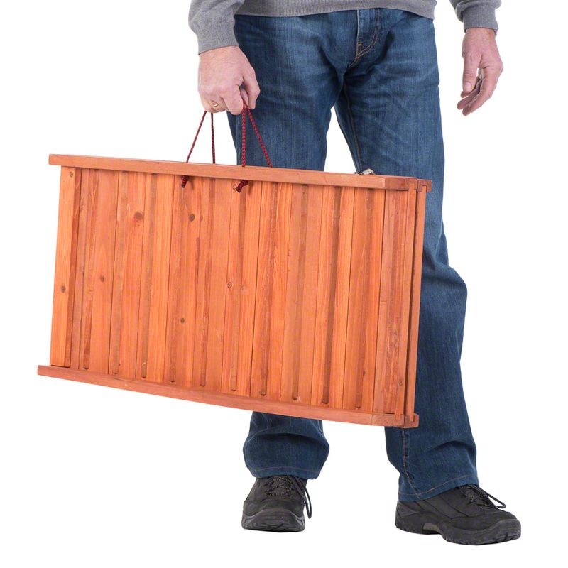 Wooden transport box with red carrying handles, carried by a person. Shows portability and size of the box.