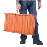 Wooden transport box with red carrying handles, carried by a person. Shows portability and size of the box.
