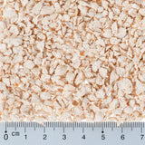 Close-up of light brown flakes with a ruler in centimetres for size reference. Flake size approximately 0 to 5 mm.
