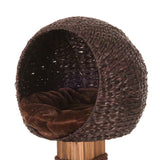 Round cat bed made of brown woven material with a soft, dark brown cushion. Bed mounted on a wooden stand.