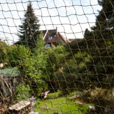 Protective net for outdoor areas, fine-meshed, transparent, with view of garden landscape in the background.