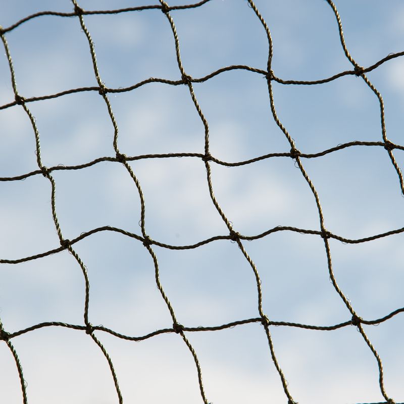 Close-up of a sturdy net made of braided rope against a blue sky, suitable for protection or separation purposes.