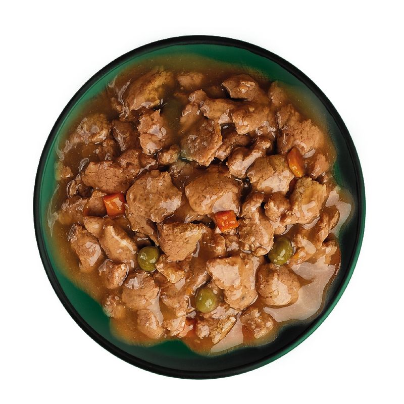 Chunks of meat in gravy with visible peas and carrot pieces served in a bowl, showing the texture and ingredients of the wet pet food.