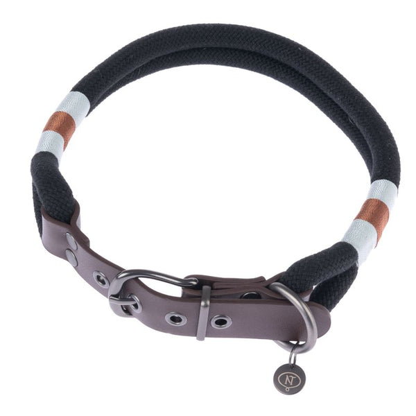 Black collar made of braided fabric with brown and white accents, metal clasp and leather details. Pendant with NT logo visible.