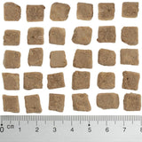 Brown, square food pieces approximately 1-2 cm in size, shown next to a ruler for size reference.
